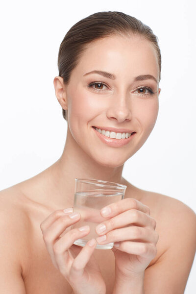 Hydration is key. A beautiful woman with bare shoulders holding a glass of water