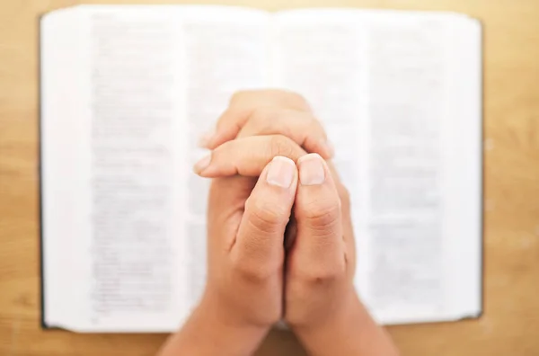 Hands, bible and desk for prayer, closeup and mindfulness for faith, religion or reading in pov. Woman, praying and study holy book for peace, mental health and worship with praise to God in top view.