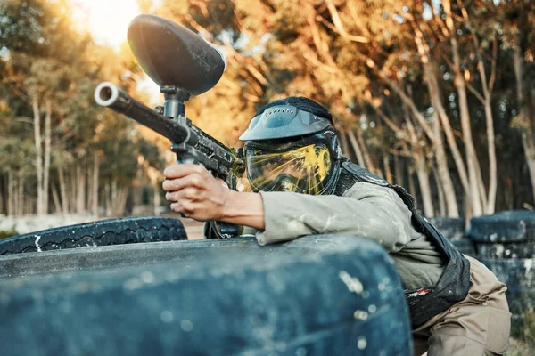 Paintball, sports and person in action with gun for tournament, competition and battle in nature. Camouflage, military and woman shooting in outdoor arena for training, adventure games and challenge.