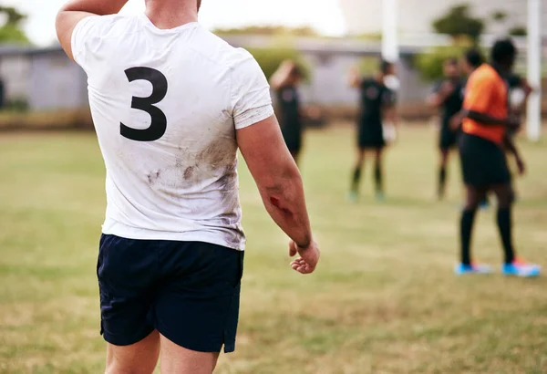 Lifes short, spend it on a rugby field. Cropped shot of a man playing a game of rugby with his teammates in the background