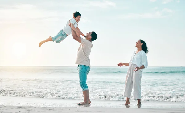 Family, beach and father lifting boy child with love, freedom and travel celebration in nature. Flying, fun and parents with kid at the ocean for bond, happy and airplane game while traveling in Bali.