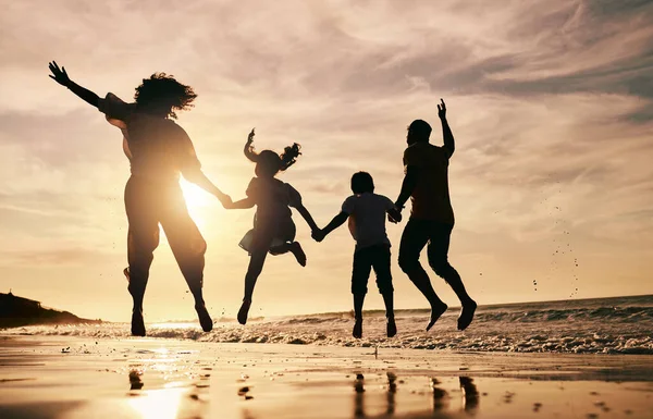 Silhouette, family jump on beach and sunset with ocean waves, back view and bonding in nature. Energy, people holding hands in air outdoor and holiday, freedom and travel, trust and love in Mexico.
