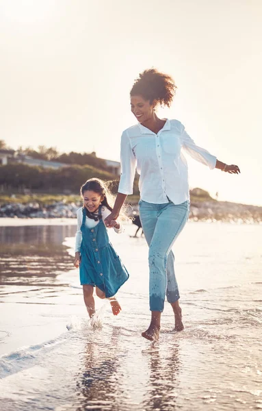 Fun, child and a mother running at the beach on a family vacation, holiday or adventure in summer. Young girl kid holding hands with woman outdoor with fun energy, happiness and love at sunset ocean.