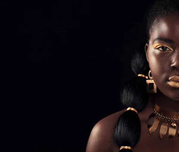 Half, portrait and black woman in studio with gold, luxury and makeup on black background. Glitter, face and African female model with wealth, glow and jewellery, elegance and posing royal aesthetic.
