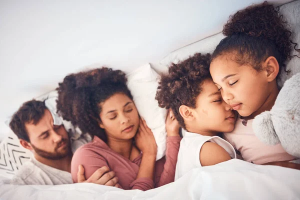 Comfort, sleeping and family in a bed with love, dreaming and resting in their home together. Sleep, nap and children with parents in a bedroom embracing, peaceful and hugging, comfortable and bond.