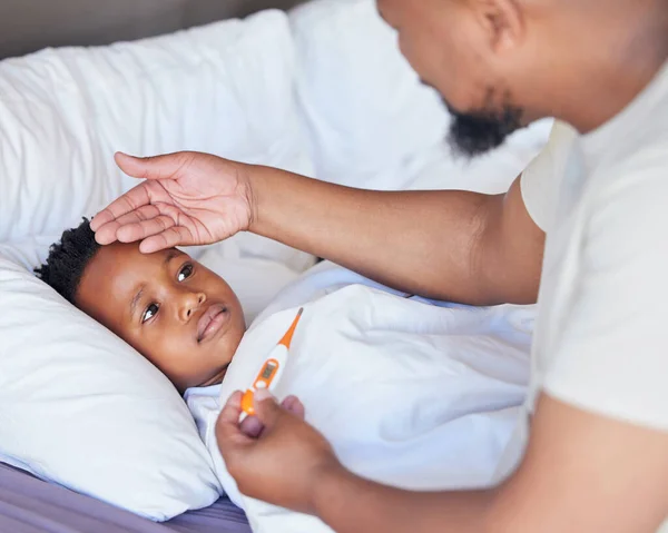 Father, thermometer and sick child in bed with a fever and hand of dad on head to check temperature. Black boy kid and a man together in a bedroom for medical risk, health test and virus problem.