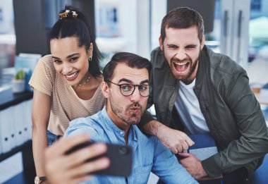 Bu dinamik takım bir aradayken asla sıkıcı bir an olmaz. Ofiste selfie çeken bir grup tasarımcının fotoğrafı.