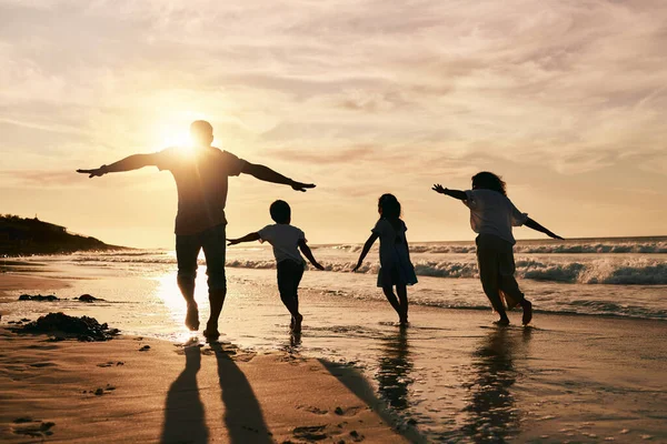 Silhouette, family is running on beach and back view with ocean waves, sunset and bonding in nature. Energy, action people outdoor on tropical holiday and freedom, travel with trust and love.
