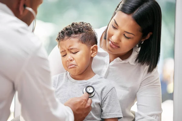 Mother, sick child and doctor with stethoscope for health care in hospital for heart and lungs. African woman, pediatrician man and kid patient cry for medical check, family insurance or development.