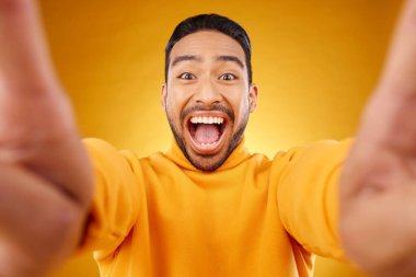 Heyecanlı, mutlu bir adamın sarı arka planda izole edilmiş portresi ve selfie 'si. Yüz, gülümseme ve sosyal medyada komik hafıza, kahkaha ve fotoğraf için profil fotoğrafı çeken Asyalı kişi.