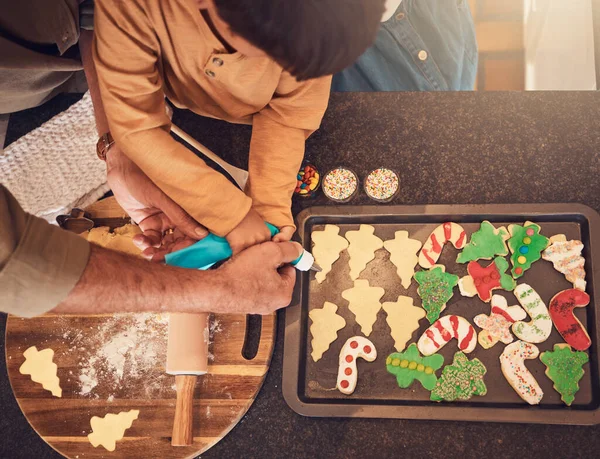 Christmas, above and a family baking cookies, help with food and process of decoration. Hands, child and teamwork for icing sweet dessert or biscuits for a festive holiday in the kitchen together.