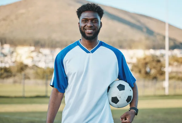 Soccer ball, football player or portrait of black man with smile in sports training, game or match on pitch. Happy, fitness or proud African athlete in practice, exercise or workout on grass field.