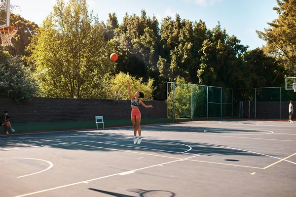Its not about how good you are, its how good you want to be. Shot of a sporty young woman throwing a basketball into a net on a sports court