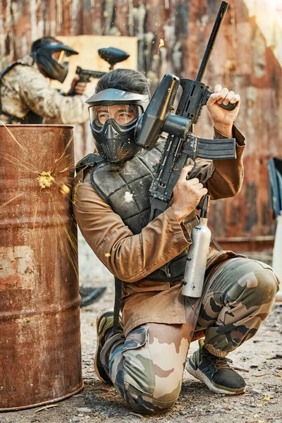 Paintball, soldier and man with gun for tournament, competition and battle in arena. Extreme sports, military and male person shooting in outdoor gear for training, adventure games and challenge.