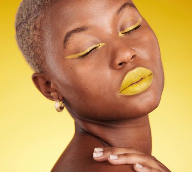 Makyajlı göz kalemi ve kozmetoloji için ruju olan bir stüdyoda kozmetik, sanat ve kadın. Güzel, yaratıcı ve genç Afrikalı kadın model. Renkli, büyüleyici bir yüzü var. Sarı arka planda.