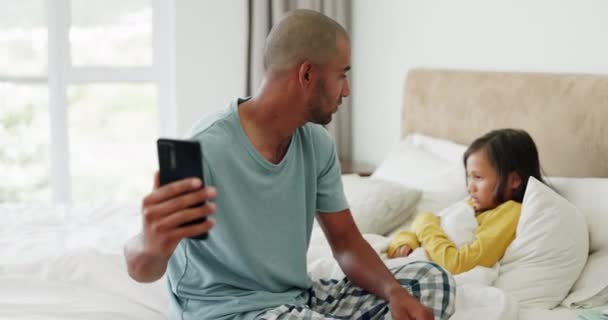 视频电话 发烧和一个父亲带着一个生病的孩子 在讲电话和照顾一个女孩在床上 当一个孩子在卧室里用手机聊天时 他的支持 房子和爸爸都会感觉到他的额头 — 图库视频影像