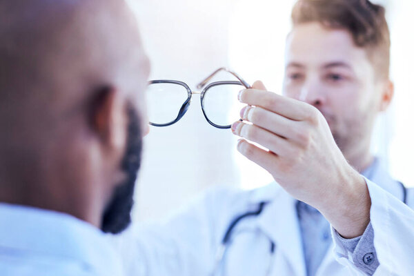 Hands, man and optometrist with glasses for eye support and lens check at a doctor consultation. Medical, wellness and back of patient with vision and eyewear care with professional holding frame.