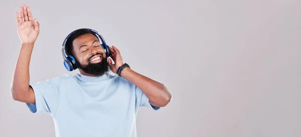 ヘッドフォン ハッピーで若い男が音楽 プレイリスト アルバムを聴きながら踊っている アフリカの男性モデルストリーミングソングまたはラジオでグレーの背景でスペースをモック — ストック写真