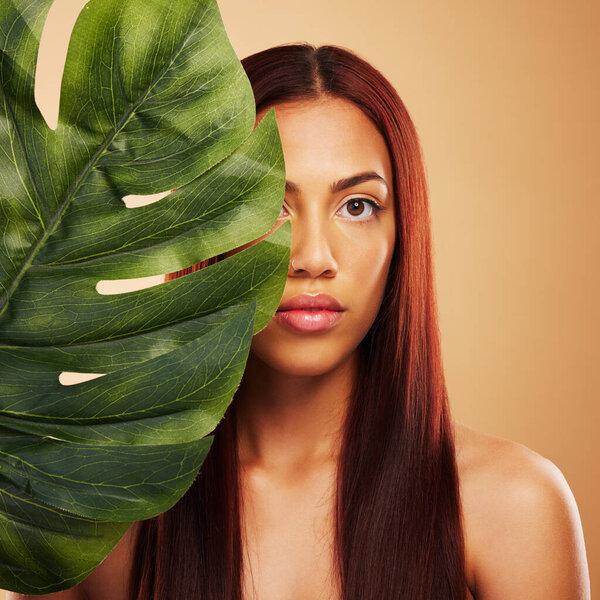Beauty, leaf and portrait of woman in studio for natural dermatology, cosmetics or wellness results. Skin care, nature and monstera plant for eco friendly facial of model person on brown background.
