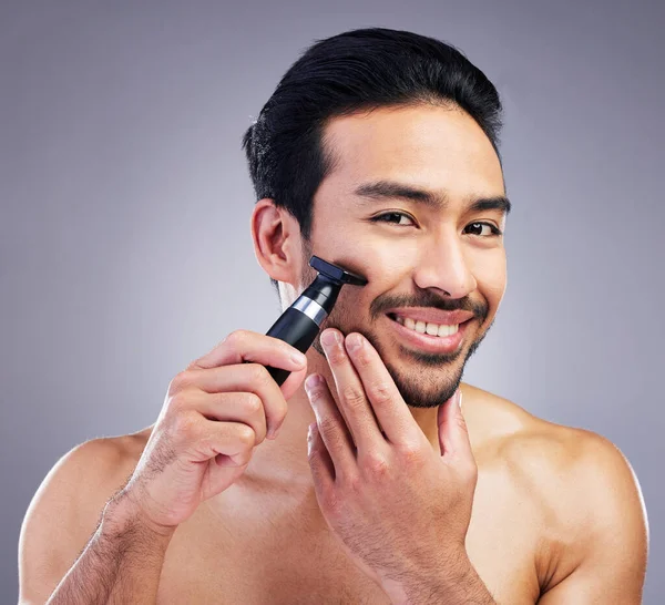 Beard hair trimmer, portrait and man smile for bathroom shaving routine, grooming or morning skincare. Studio razor, facial growth maintenance and Mexican person with clean face on gray background.