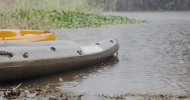 Kayak, rain and nature with adventure and journey on a river with paddle for fitness and exercise. Outdoor, rowing and boat for workout for water sports with travel on a lake on holiday in woods.