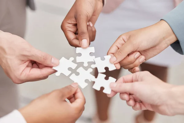 Business people, hands and puzzle for teamwork, mission and problem solving of challenge, synergy and cooperation. Closeup of employees with jigsaw for integration, collaboration or planning solution.