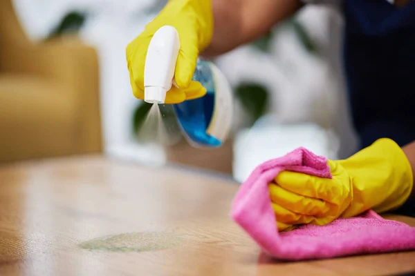 stock image Spray, hands and person cleaning table, furniture and housekeeping services at home. Closeup of cleaner wipe surface with cloth, bottle of chemical product and disinfection of dust, bacteria and dirt.