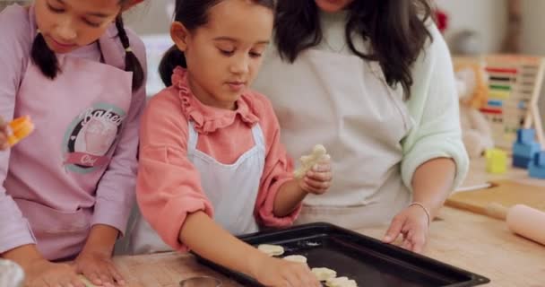 家庭用キッチンカウンターで焼くことを学ぶおばあちゃん お母さん 子供たちは スキルやケアとしてデザートを準備します 少女がクッキーのレシピや食べ物を子供たちに教えたり助けたりする — ストック動画