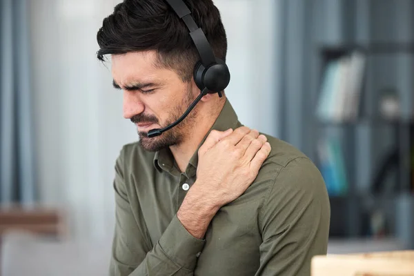 Call center man, shoulder pain and stress in office, communication expert or consultant with emergency. Young telemarketing agent, crm and muscle injury with accident, problem or fatigue in workplace.
