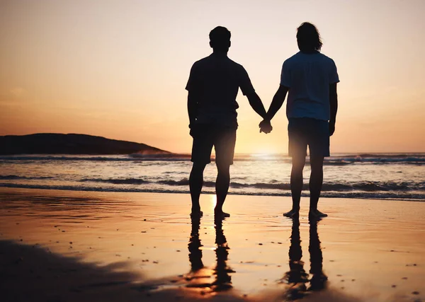 Silhouette, holding hands and gay couple on beach, sunset and nature on summer vacation together in Thailand. Sunshine, ocean and romance, lgbt men on island and fun holiday with pride, sea and waves.