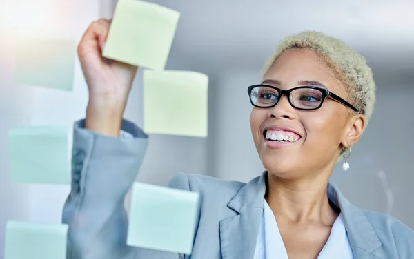 Writing, planning and happy business woman in office with sticky note goal, idea or strategy. Schedule, smile and happy female manager brainstorming calendar, mission or agenda, management or growth.