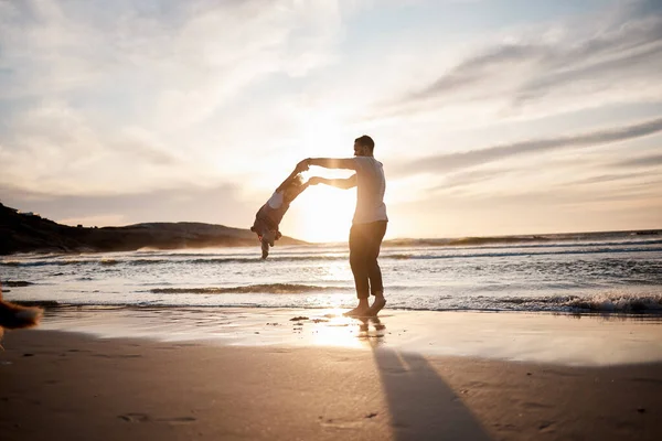ビーチで子供とスウィング 父親は 日没の絆のために自然に手を握っています バリ島で遊び ゲーム お祝いをするために海で子供と旅行と親 — ストック写真