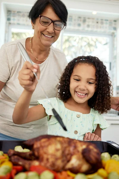 Kitchen, food and a grandmother cooking with her grandchild in their home together for thanksgiving. Children, love and a roast with a senior woman preparing a meal with a girl for healthy nutrition.