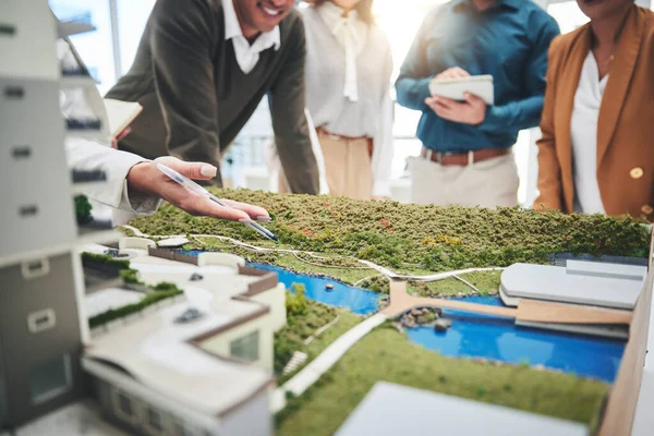 Creative people, hands and real estate with 3d model of building design, architecture or property at office. Closeup of group architect team in meeting, project planning or floor layout at workplace.