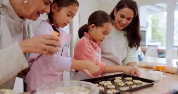 家庭用キッチンカウンターで焼くことを学ぶおばあちゃん お母さん 子供たちは スキルやケアとしてデザートを準備します 女の子はクッキーのレシピや食べ物で子供たちを教えたり助けたりします — ストック動画