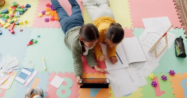 タブレット 少女の子供たちは 発達のために 上記から一緒に家にいます テクノロジー 寝室の床に横たわっている姉妹の子供たちとの宿題 — ストック動画