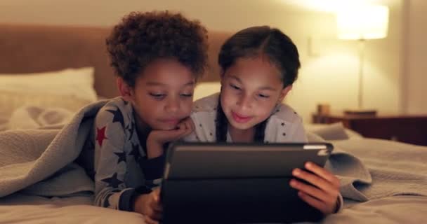 子供たちは一緒に タブレットのビデオを見て 娯楽のために自宅でコメディとベッドで 兄弟姉妹 テクノロジー 夜に寝室で映画やゲームをストリーミングしたり アプリでリラックスしたり — ストック動画
