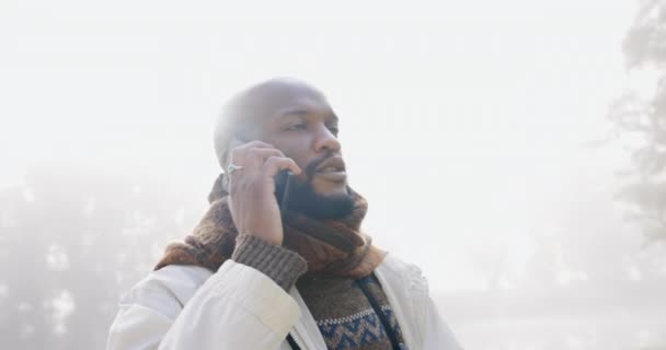 コミュニケーション チャット 会話のための冬の電話で考える 黒人の男と自然 午前中に公園の霧の中でモバイルで話すアフリカ人の笑顔とアイデア — ストック動画