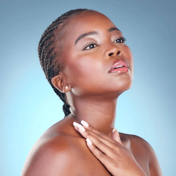 Beauty, skin care and glow of a black woman with dermatology, natural makeup and manicure. Face of African person on blue background with facial cosmetics and hand for soft touch or nails in studio.