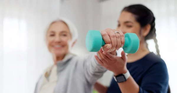 Woman, nurse and dumbbell in elderly care for physiotherapy, exercise or workout at old age home. Female doctor, caregiver or personal trainer helping senior patient in weightlifting for healthy body.