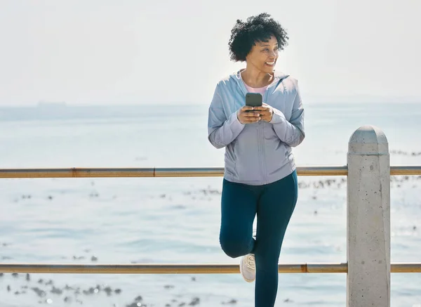Happy, phone and fitness with black woman at beach for running, workout and mockup. Network, communication and contact with female runner training in nature for technology, sports and mobile.