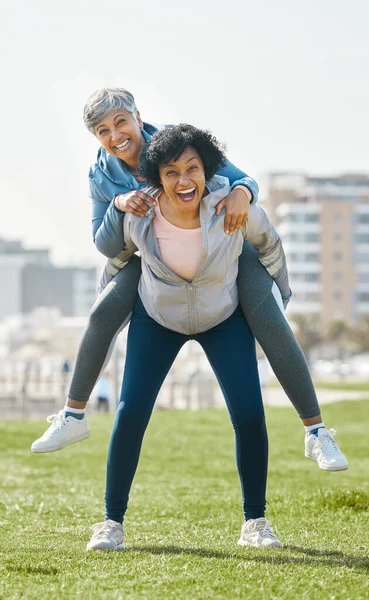 City, funny and senior women piggyback together playing, crazy and funny with as friends for outdoor exercise. Health, wellness and portrait of crazy elderly people bonding and laughing after workout.