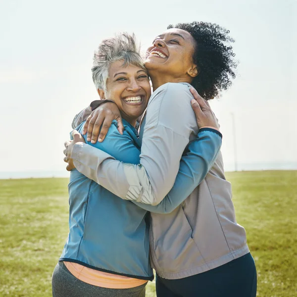 Hugging, fitness and senior women bonding together in an outdoor park after a workout or exercise. Happy, smile and elderly female friends or athletes with love and care after training in nature