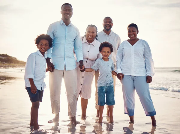 Happy, relax and portrait of black family at beach for travel, summer break and bonding on vacation. Smile, holiday trip and generations with parents and children for quality time, sunshine and fun.