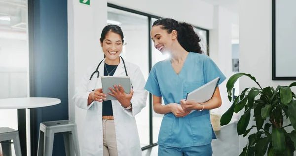 Talking doctor, walking or nurse on tablet in busy hospital teamwork, women collaboration or bonding with surgery joke. Smile, happy or laughing healthcare workers on medical technology meme or comic.
