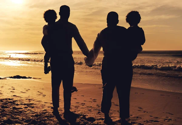 Beach, holding hands and family in sunset silhouette for summer vacation, holiday and travel love with children. Parents or people together with kids rear by ocean or sea for bonding, peace and care.