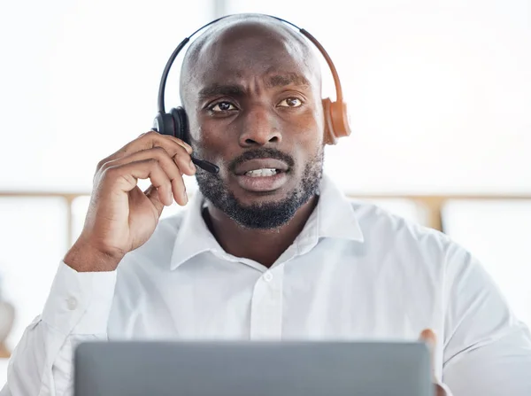 Black man thinking while consulting on laptop in call center for customer service, advisory and questions. Face of serious salesman working in CRM agency for telecom solution, tech support and help.
