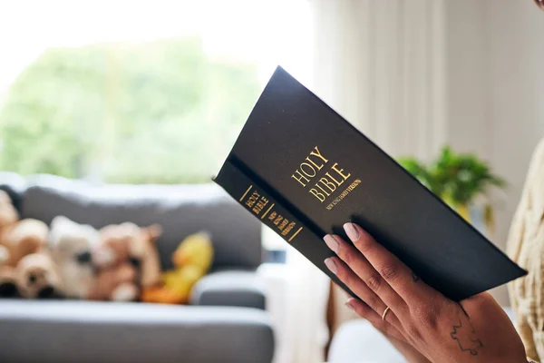 Closeup, bible and hands in home for faith, studying religion or mindfulness with holy spiritual scripture. Christian literature, reading and ethics for knowledge, language or woman with Jesus Christ.