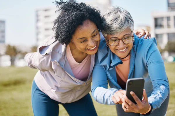 Senior woman, friends and outdoor with phone or social media, blog or reading post about workout, exercise and walk in park. Elderly person, people and check profile picture together on screen.