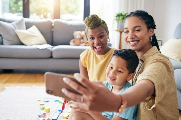 Lesbian, women and son in family selfie, smile or care with toys, post or web blog on floor in home living room. Mother, male kid and happy for love, bonding or memory for social network app in house.